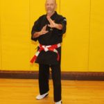 Hanshi Jeff Ader | Okinawa Karate knife hand Block in front of a yellow wall